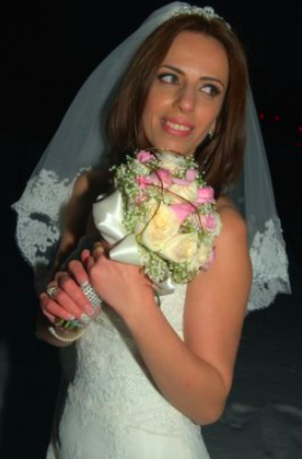 Beautiful bride holding pink and white flowers looking over her shoulders smiling