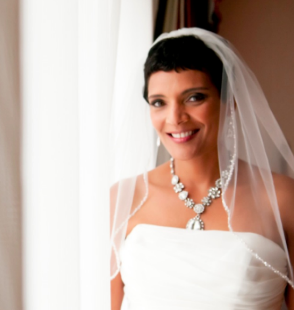 Beautiful bride smiling in her veil dress and jewelry near a bright window